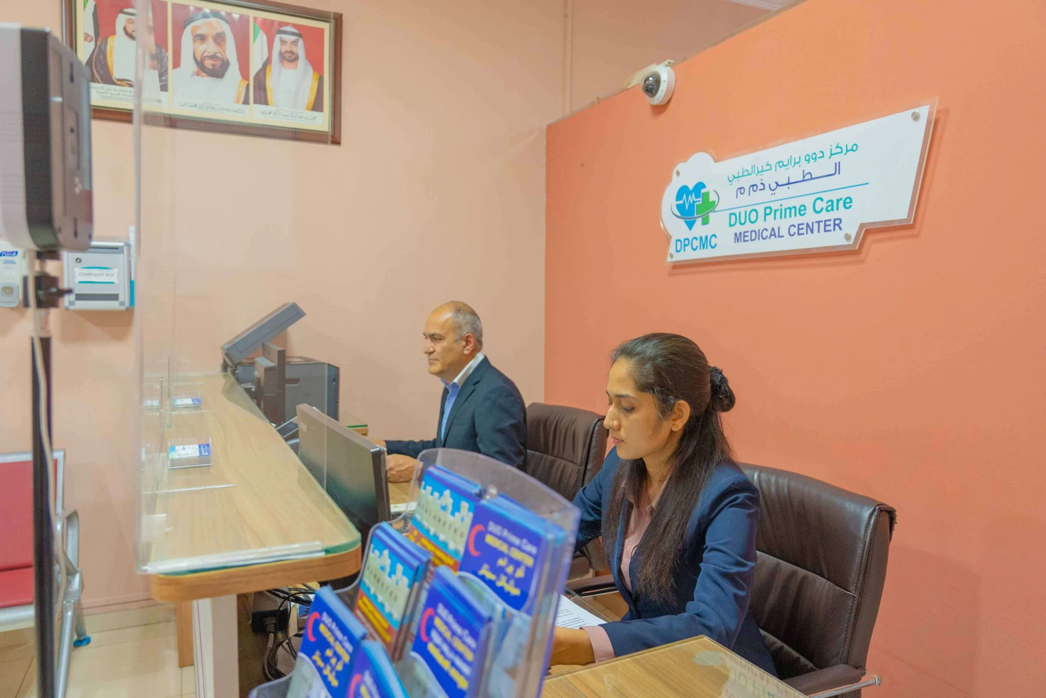 The reception desk at Duo Prime Care, with the clinic's sign on the wall behind the receptionists